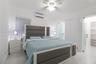 Neutral-toned interior featuring large-format tile flooring, a wall-mounted ductless air conditioning unit, a ceiling fan with integrated lighting, an