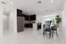 Kitchen featuring dark-toned cabinetry, a stone-finish countertop island with a breakfast bar, stainless steel appliances, a mosaic-tile backsplash, a