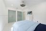 Room featuring white stone-finish flooring, recessed lighting, a modern circular ceiling fan, and two glass-panel doors with matte metal hardware