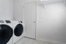 Laundry room featuring large-format tile flooring, a six-panel door with brushed nickel hardware, and an overhead built-in white storage shelf
