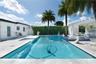 Outdoor swimming pool featuring a tiled finish, raised spa with mosaic tiling, stone-paved decking, and a covered pergola