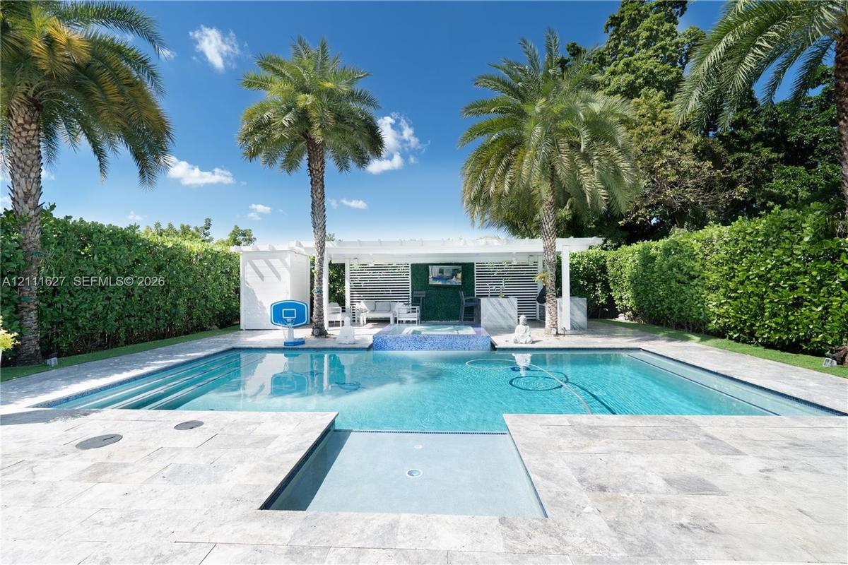 Swimming pool with built-in spa, stone paver patio, covered cabana, and perimeter privacy hedges