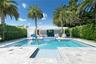 Swimming pool with built-in spa, stone paver patio, covered cabana, and perimeter privacy hedges