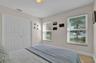Neutral-toned walls, double-door closet with recessed paneling, and dual windows equipped with horizontal blinds, complemented by light-colored tile f