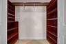 Walk-in closet featuring custom wood-finish shelving units, integrated hanging rods, and tile flooring