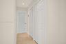 Neutral-toned interior space featuring stone flooring, a door with a frosted glass panel, and dual built-in closets with white louvered and paneled do