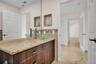 Dark wood-finish cabinetry featuring a stone-look countertop, integrated glass vessel sink, nickel-finish faucet, and built-in wall niches