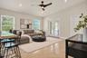 High-ceilinged living area featuring stone-finish flooring, a contemporary three-blade ceiling fan, recessed lighting, and glass-paneled double doors
