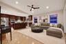Open-concept interior featuring vaulted ceilings, polished tile flooring, recessed lighting, and a kitchen equipped with dark wood-finish cabinetry, a