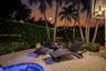 Paver patio featuring a built-in spa, mature palm trees, and privacy-focused hedge landscaping