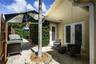 Outdoor patio featuring herringbone-patterned pavers, a circular stone-lined tree planter, and dual-pane glass entry doors