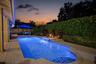 Backyard swimming pool featuring integrated water features, a paver stone deck, and mature privacy hedging