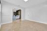 Large-format neutral tile flooring, smooth ceilings, and white interior doors