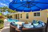 Outdoor living area featuring a paved brick patio, a built-in swimming pool, and tropical landscaping