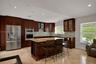 Kitchen featuring dark wood cabinetry, stainless steel appliances, stone countertops, integrated wine storage, and stone-finish flooring
