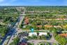 Aerial perspective of property featuring mature canopy trees, paved circular driveway, and white roofing systems