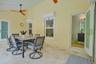 Covered patio featuring stone tile flooring, two ceiling-mounted fans, multiple glass-paneled entry doors, and wall-mounted ductless climate control u
