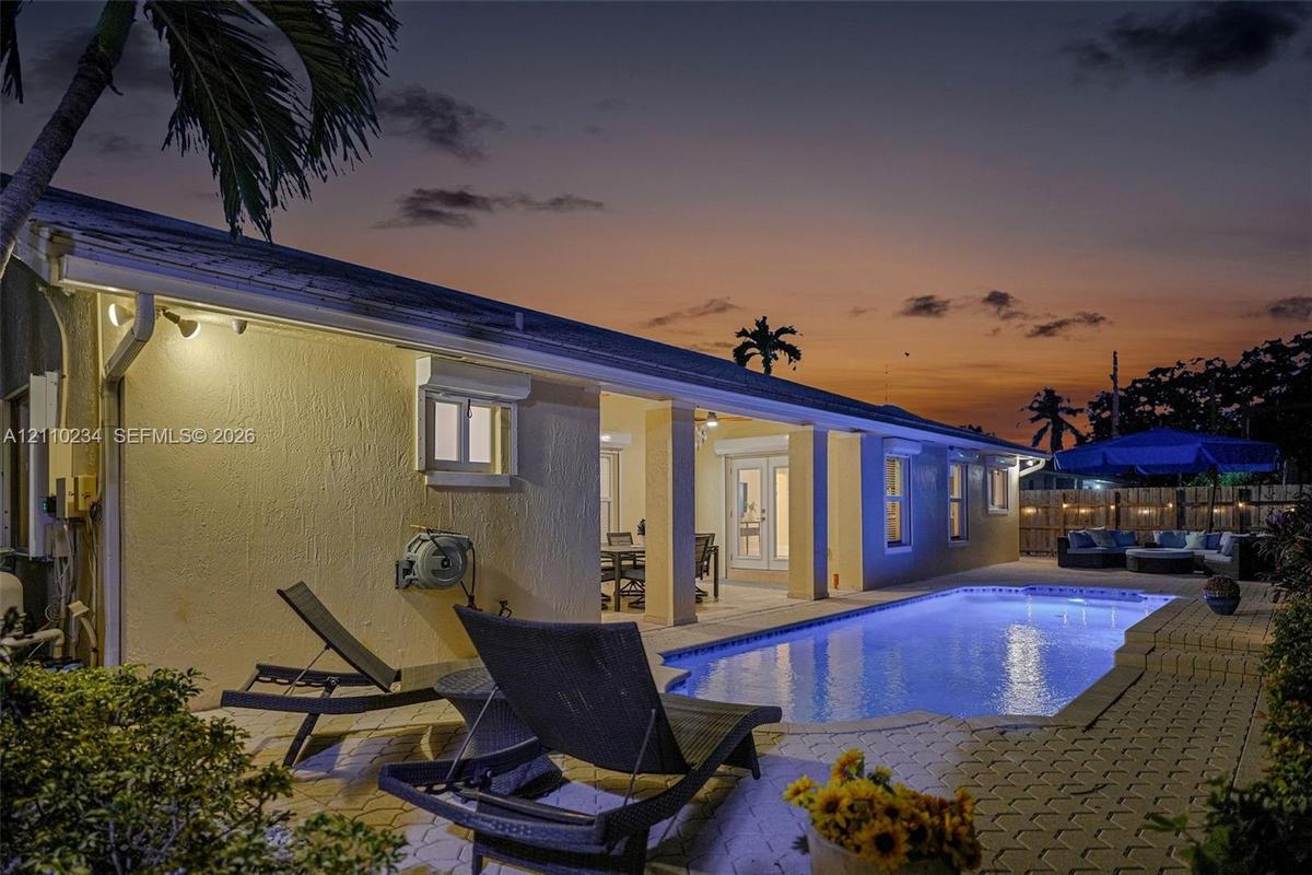 Outdoor space featuring a rectangular in-ground swimming pool, paver patio, covered lanai, and exterior wall-mounted lighting