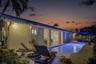 Outdoor space featuring a rectangular in-ground swimming pool, paver patio, covered lanai, and exterior wall-mounted lighting