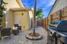 Paver patio featuring a stone-bordered tree planter, integrated wall-mounted lighting, and wood privacy fencing