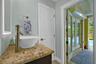 Vanity featuring a stone countertop, vessel sink with a high-arch faucet, and an integrated LED-backlit mirror, with double French doors opening to an