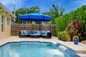 In-ground swimming pool featuring a decorative water feature and paver stone decking enclosed by a privacy fence and mature perimeter landscaping