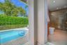 In-ground pool with stone paver surround, recessed shower lighting, glass-enclosed shower stall with tile wall, and stucco exterior walls