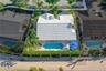 Aerial perspective of property featuring a light-toned tile roof, an in-ground swimming pool with a hardscaped deck, and mature palms within a fenced 
