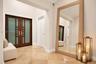 Double entry doors featuring frosted glass panels and metallic hardware, complemented by large-format stone tile flooring