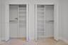 Dual closets featuring white bi-fold doors, built-in shelving units, and integrated clothing rods