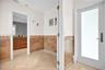 Entry area featuring large-format diagonal tile flooring, wall-mounted hardware, and wainscoting with decorative tile accents