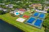 Recreational complex featuring two fenced tennis courts, a basketball court, an outdoor swimming pool, and a sand playground area