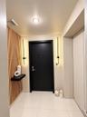 Entryway featuring vertical wood slat paneling, large-format tile flooring, a matte black door, dual linear wall-mounted light fixtures, and a floatin