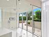 Steam room featuring full-height glass walls, wall-mounted handheld shower fixture, recessed ceiling lighting, and porcelain tile flooring