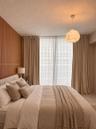 Vertical wood-slat accent wall, full-height window drapery, and suspended textured pendant lighting
