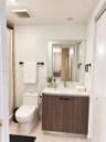 Bathroom featuring a vanity with a wood-finish cabinet, solid surface countertop, integrated rectangular sink, wall-mounted mirror, and matte black ha