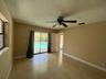 Spacious room with tile flooring and a ceiling fan, featuring a sliding glass door providing direct access to a private pool area