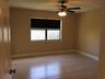 Neutral-toned interior room featuring tile flooring, a window with a roller shade, and a ceiling fan with integrated lighting