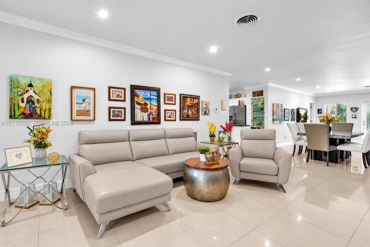 Open-concept floor plan featuring light-toned tile flooring, recessed lighting, and crown molding