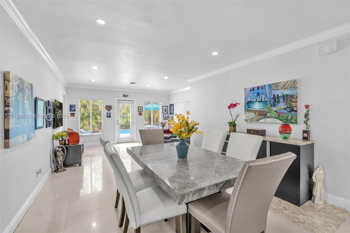 Open-concept interior featuring large-format tile flooring, recessed lighting, and crown molding