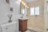 Room featuring large-format tile flooring, crown molding, and dual windows with horizontal blinds