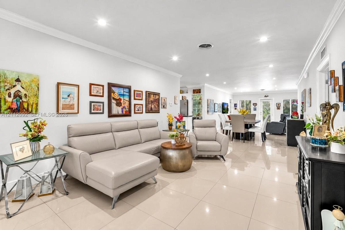 Neutral-toned polished tile flooring, recessed lighting, crown molding, and a front entry door featuring frosted glass paneling