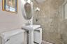 Neutral-toned tile flooring, crown molding, and dual windows equipped with horizontal blinds