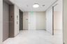 Common area featuring large-format white stone-finish tile flooring, dual elevators with metallic finishes, and recessed ceiling lighting