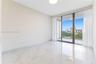 Interior space featuring large-format stone-finish floor tiling, floor-to-ceiling glass sliding doors, and access to a covered outdoor balcony