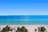 Oceanfront perspective featuring a wide sandy beach, turquoise waters, and mature palm trees