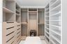Custom walk-in closet featuring extensive built-in shelving, multiple hanging rods, and integrated storage drawers with cutout handles
