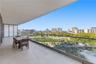 Expansive covered balcony featuring large-format stone tile flooring and a sleek frameless glass railing