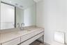 Floating vanity featuring wood-finish cabinetry, stone countertop with an integrated rectangular sink, wall-mounted polished chrome faucet, and a larg