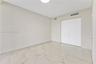 Neutral-toned room featuring large-format tile flooring with marble-pattern veining and double-door closet cabinetry